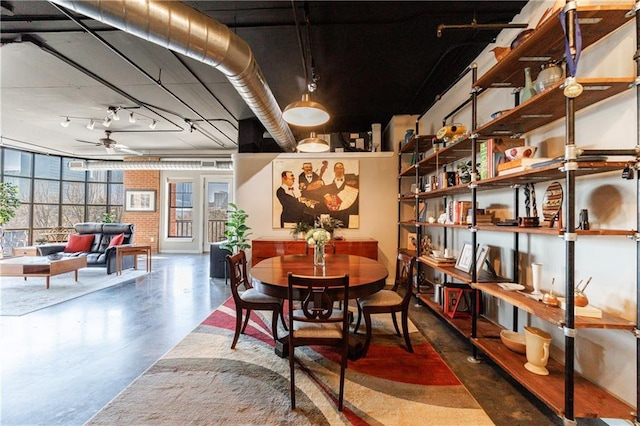 dining room featuring ceiling fan, rail lighting, and finished concrete floors