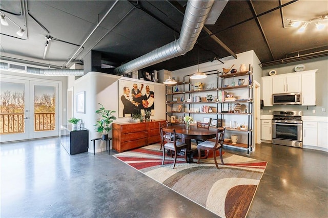 dining room with finished concrete flooring, french doors, and track lighting