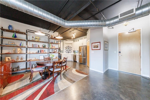 dining area featuring finished concrete flooring, visible vents, and baseboards