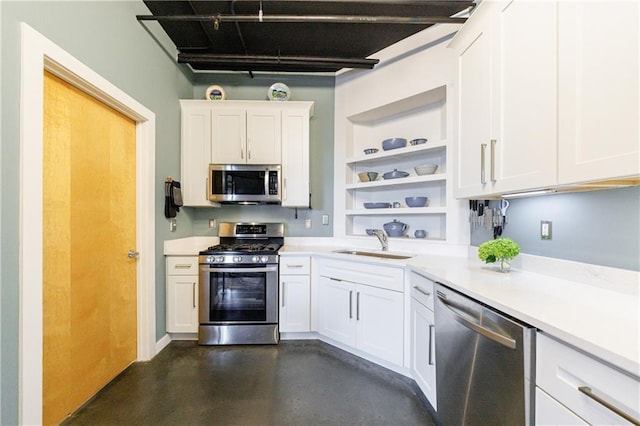 kitchen with appliances with stainless steel finishes, light countertops, a sink, and open shelves