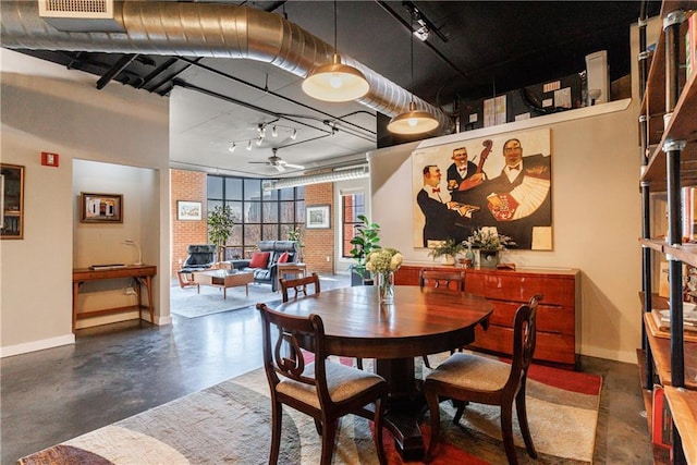 dining area with baseboards, brick wall, ceiling fan, finished concrete floors, and track lighting