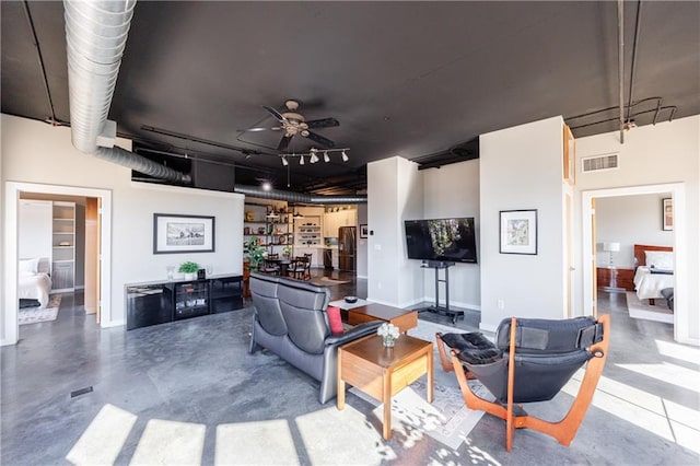 living room featuring finished concrete flooring, rail lighting, visible vents, and a ceiling fan