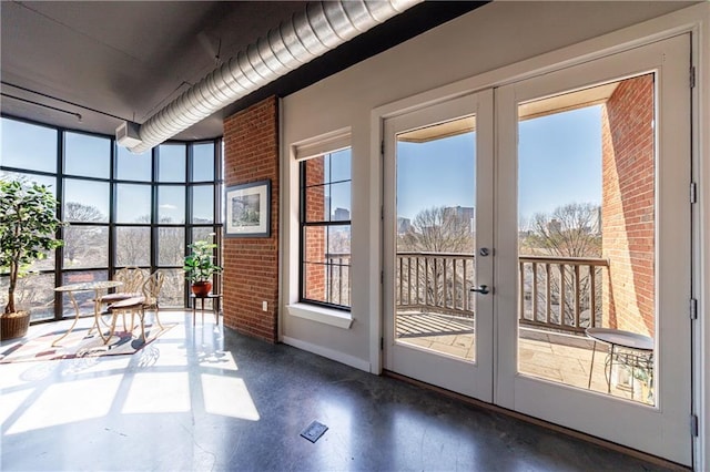 entryway featuring finished concrete floors, french doors, baseboards, and brick wall