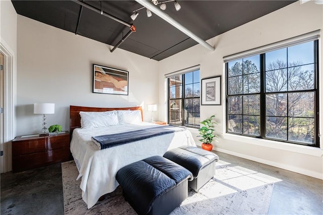 bedroom with concrete flooring, rail lighting, and baseboards