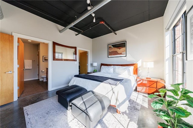 bedroom with ensuite bath and baseboards