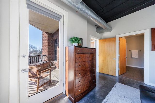 bedroom featuring access to exterior, baseboards, and finished concrete floors