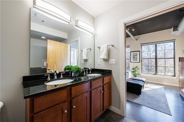 bathroom featuring a sink, baseboards, and double vanity