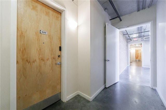 hall featuring finished concrete flooring and baseboards