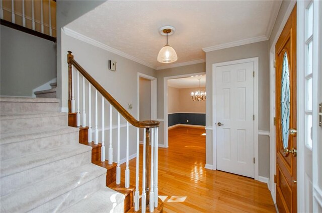 entrance foyer featuring hardwood / wood-style flooring, crown molding, and a notable chandelier