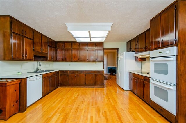 kitchen with white appliances, light hardwood / wood-style floors, and a textured ceiling