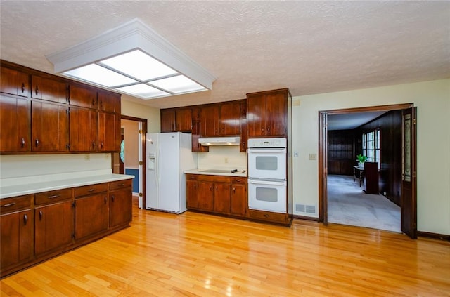 kitchen with white appliances, light hardwood / wood-style floors, and a textured ceiling