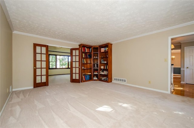 empty room featuring ornamental molding, light colored carpet, a textured ceiling, and french doors