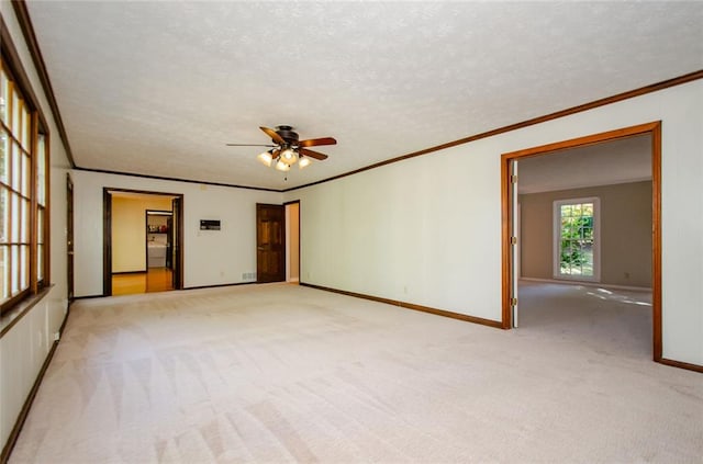 carpeted empty room featuring ceiling fan, crown molding, and a textured ceiling