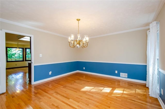 empty room featuring hardwood / wood-style flooring, crown molding, and a notable chandelier