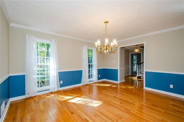 empty room featuring wood-type flooring, a notable chandelier, and crown molding