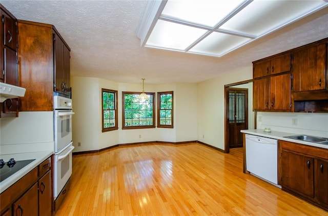 kitchen featuring white appliances, decorative light fixtures, light hardwood / wood-style floors, and a textured ceiling