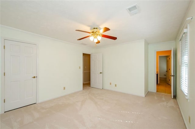 unfurnished bedroom featuring ornamental molding, light colored carpet, and ceiling fan