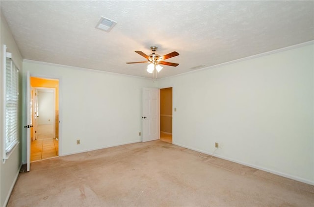 empty room featuring crown molding, ceiling fan, light carpet, and a textured ceiling