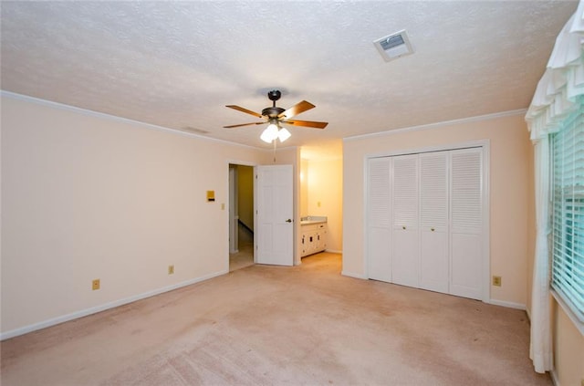 unfurnished bedroom featuring light carpet, ceiling fan, ornamental molding, and a textured ceiling