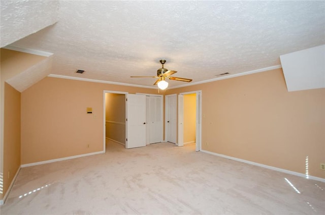 interior space with ceiling fan, vaulted ceiling, light colored carpet, and a textured ceiling