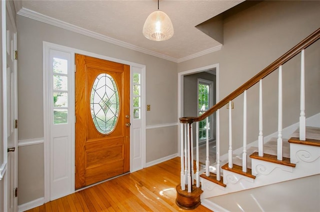 entryway with crown molding and light hardwood / wood-style floors