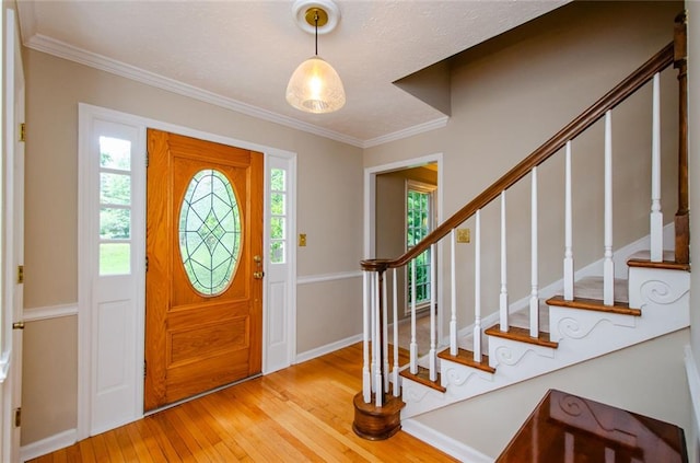 foyer entrance with light hardwood / wood-style flooring and ornamental molding