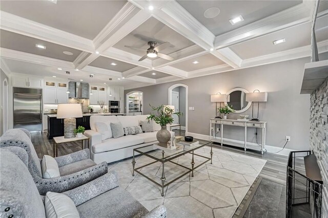 2444 Ballantrae Cir, Cumming, GA 30041 - living room featuring beam ceiling, light wood-style floors, arched walkways, a ceiling fan, and coffered ceiling