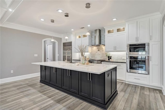 2444 Ballantrae Cir, Cumming, GA 30041 - kitchen with baseboards, wall chimney range hood, white cabinets, arched walkways, and appliances with stainless steel finishes