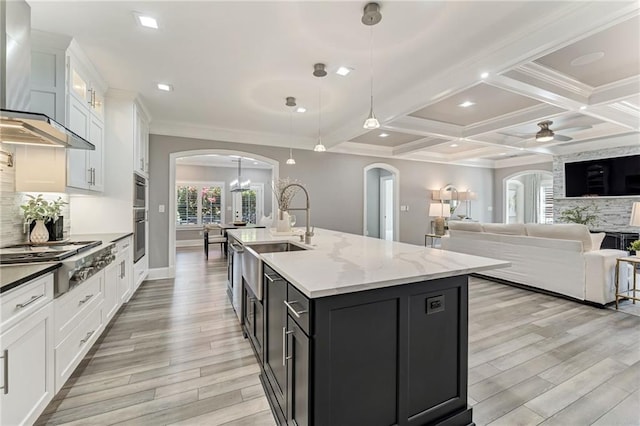 2444 Ballantrae Cir, Cumming, GA 30041 - kitchen with wall chimney range hood, arched walkways, a sink, and stainless steel gas stovetop