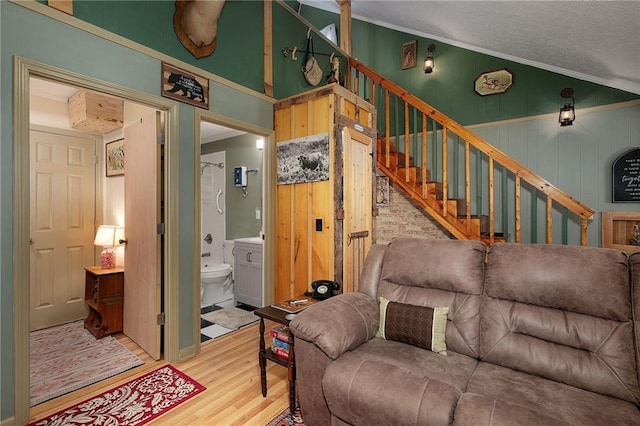 living room featuring crown molding, stairs, vaulted ceiling, wood finished floors, and a textured ceiling