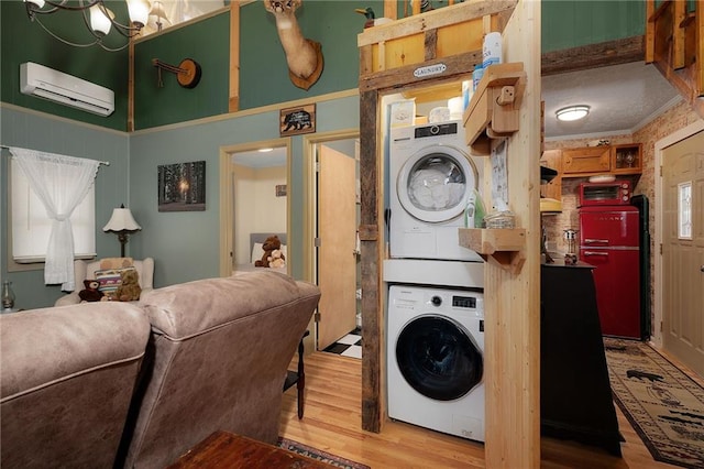 washroom with crown molding, a wall unit AC, laundry area, stacked washer and clothes dryer, and wood finished floors