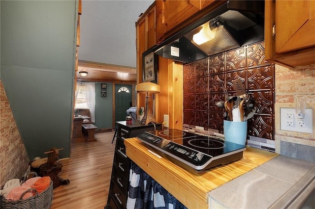 kitchen with under cabinet range hood, stovetop, wood finished floors, and brown cabinetry