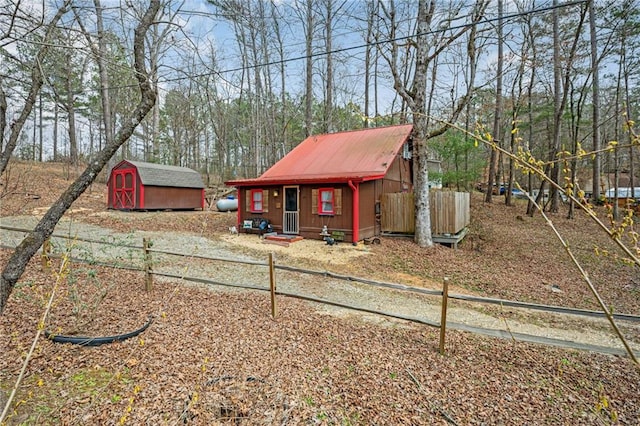 view of front of house featuring an outdoor structure, fence, a shed, and metal roof