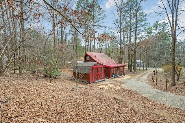 view of yard with a forest view, a storage unit, and an outbuilding