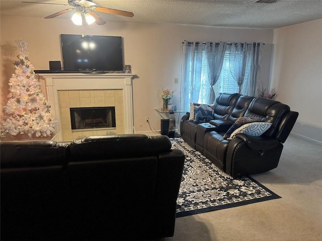 carpeted living room featuring visible vents, a ceiling fan, a textured ceiling, a tile fireplace, and baseboards