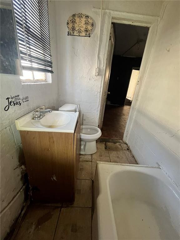 bathroom with a bathtub, vanity, and toilet