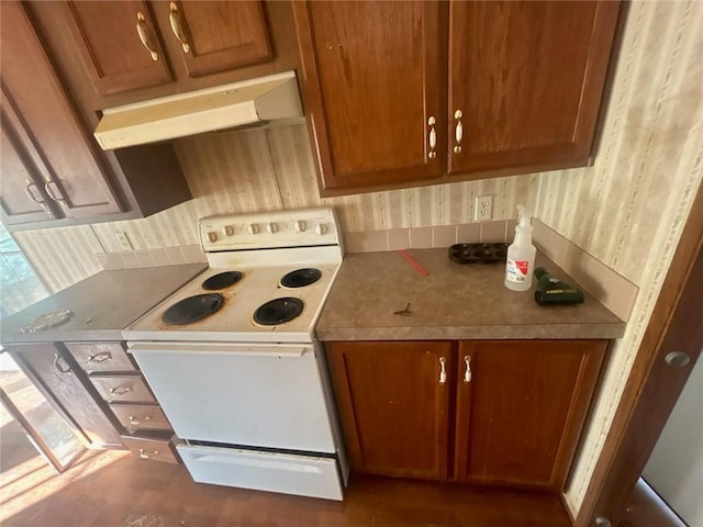 kitchen with brown cabinetry, wallpapered walls, under cabinet range hood, and white electric stove