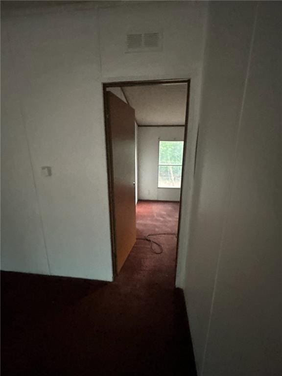 hallway featuring dark colored carpet and visible vents
