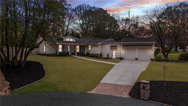 view of front facade with a garage, concrete driveway, a front lawn, and stucco siding