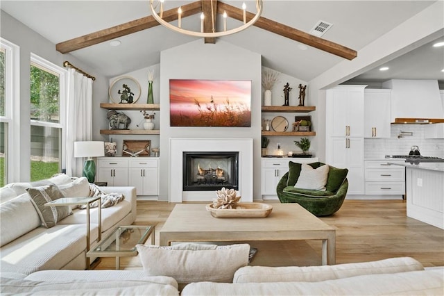 living area featuring vaulted ceiling with beams, a lit fireplace, visible vents, and light wood-style floors