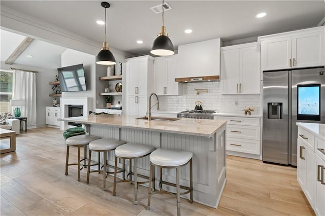 kitchen featuring a sink, visible vents, backsplash, custom exhaust hood, and stainless steel fridge with ice dispenser