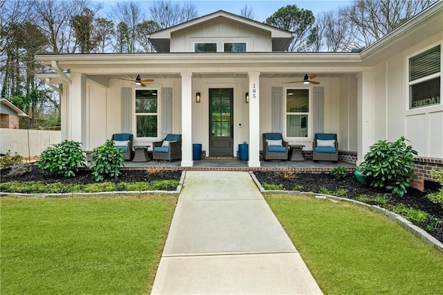 view of exterior entry featuring a porch, a lawn, board and batten siding, and ceiling fan