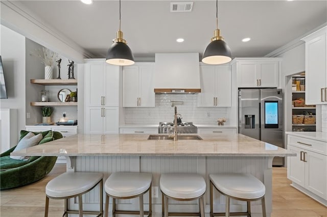 kitchen featuring light wood finished floors, visible vents, stainless steel fridge with ice dispenser, custom range hood, and a sink