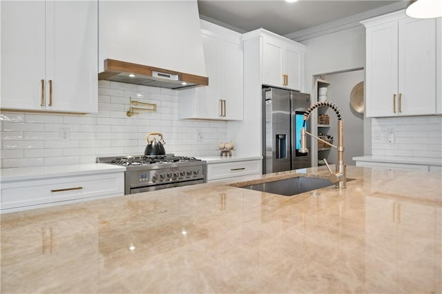 kitchen featuring stainless steel appliances, white cabinetry, a sink, and light stone countertops