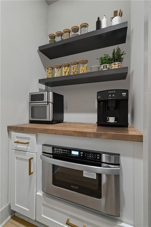 interior space with white cabinets, wood counters, and open shelves