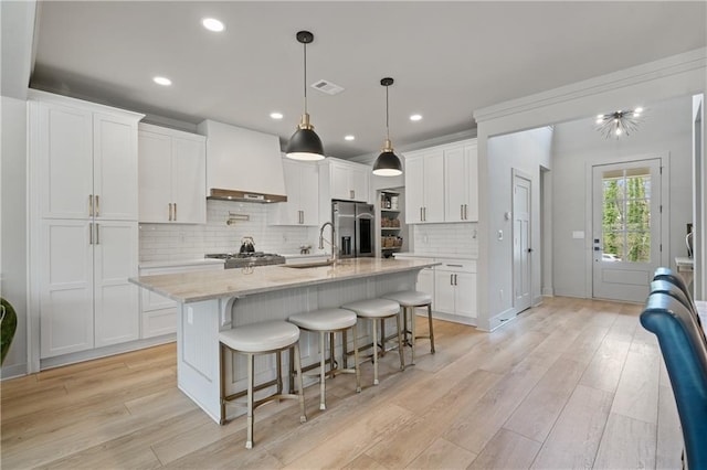 kitchen featuring a breakfast bar, stainless steel fridge, custom range hood, and light wood finished floors