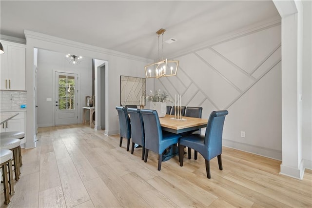 dining room with ornamental molding, baseboards, light wood finished floors, and an inviting chandelier