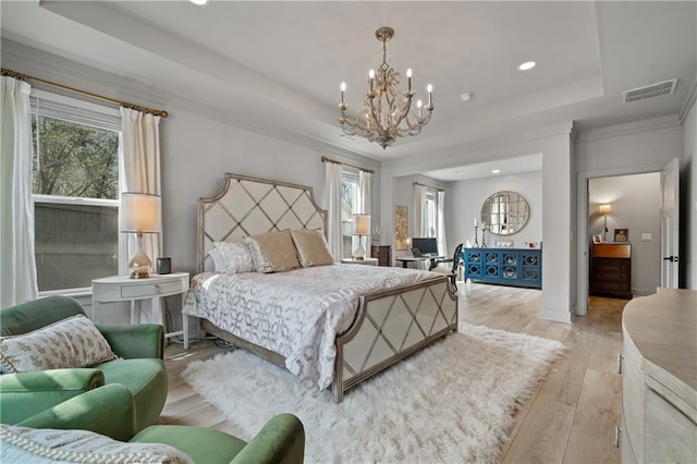 bedroom featuring light wood-style floors, visible vents, multiple windows, and a tray ceiling