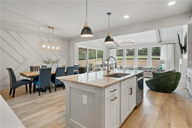 kitchen with a chandelier, a sink, open floor plan, stainless steel dishwasher, and light wood finished floors