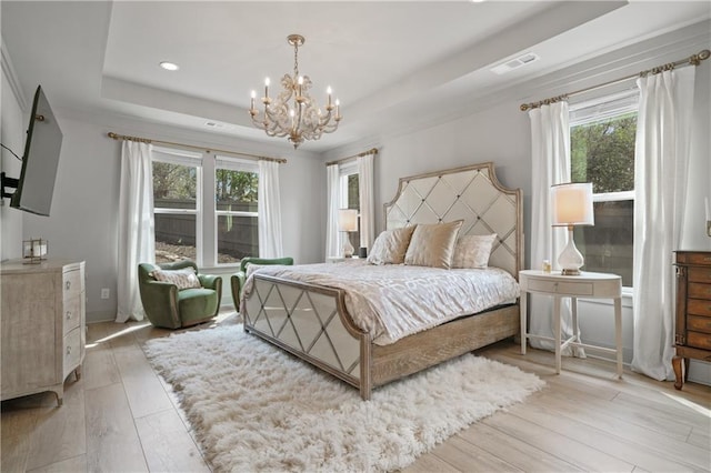 bedroom featuring a raised ceiling, visible vents, light wood-style floors, a chandelier, and baseboards